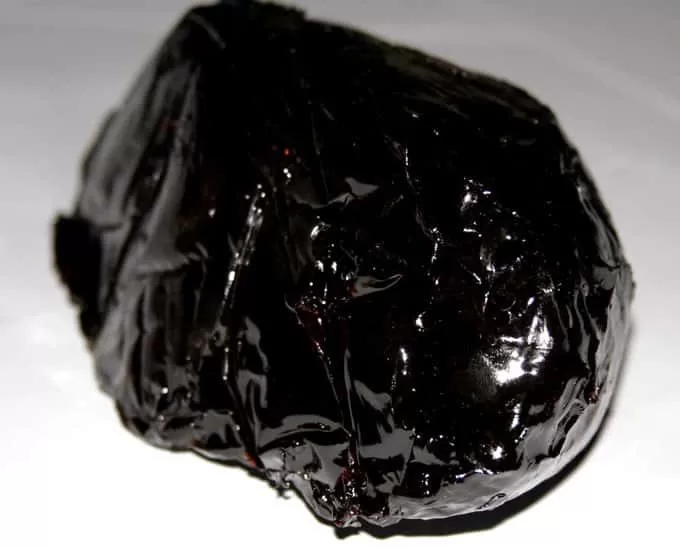 Imagen que muestra un trozo de resina de Kratom, de color negro reluciente